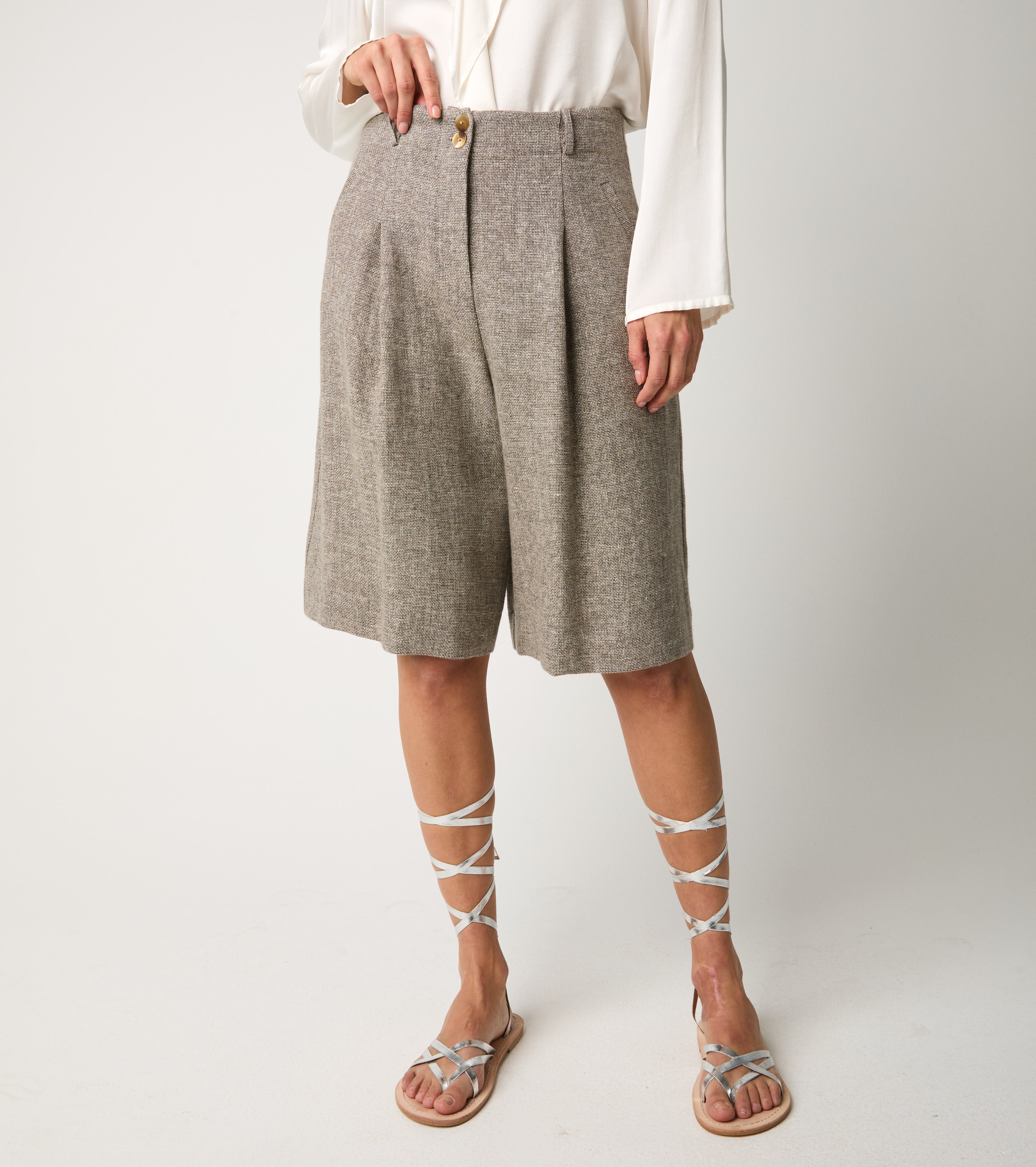 Bermuda donna eleganti in tessuto effetto tweed beige, con pinces frontali e sandali lace-up metallizzati.